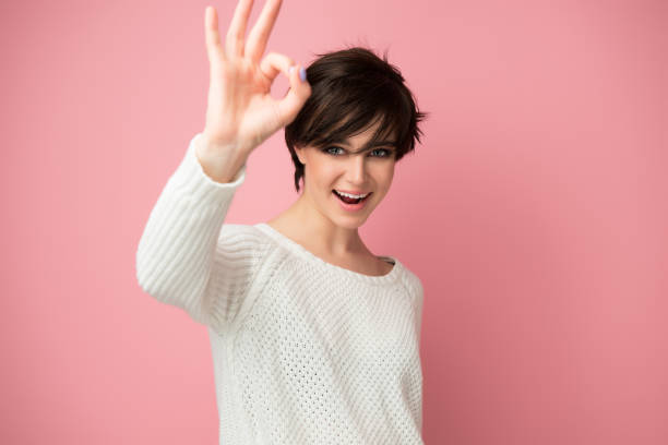 Female portrait with positive expressions and ok gesture. Beautiful young woman happy and excited expressing winning gesture. Successful and celebrating victory, triumphant, studio shot over pink background. stock photo