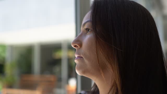 Mature woman contemplating looking through the window at home