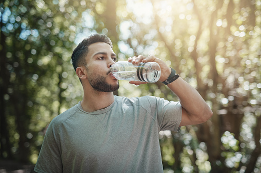 Shot of a young man drinking water after a workout