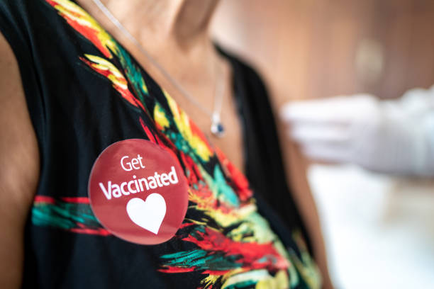istock 'Get Vaccinated' sticker glued on senior woman's clothes after being vaccinated at home 1311670872