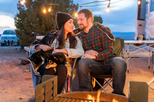 istock Young Couple Sitting By A Campfire Romantically Looking At Each Other Lovingly, Enjoying The Outdoors, Camping 1311671002