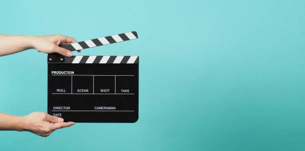 Hand is holding Black clapper board or movie slate on green or mint or Tiffany Blue background. Hand is holding Black clapper board or movie slate on green or mint or Tiffany Blue background. clapperboard stock pictures, royalty-free photos & images