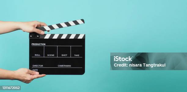 Hand Is Holding Black Clapper Board Or Movie Slate On Green Or Mint Or Tiffany Blue Background Stock Photo - Download Image Now