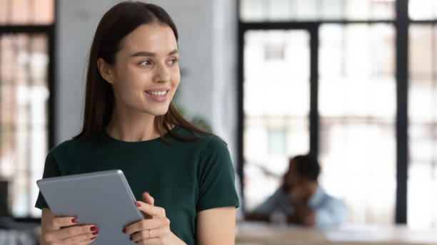 istock Smiling young woman looking aside while working at digital pad 1311672655