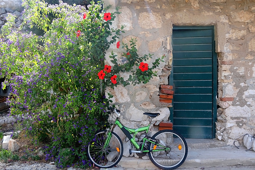 Old bike parked in front of a Mediterranean house with beautiful garden. Picturesque scenery on island Lastovo, Croatia.