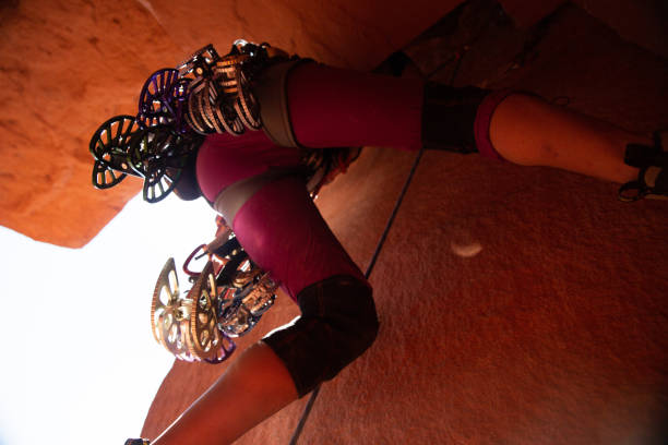 Young Woman Rock Climber at Wall Street near Moab Utah.  Athletic caucasian climber is rappelling down a cliff wearing crop pants and a lime green tank top, she has blond hair with a pony tail.  There is ample copy space in the image for titles and other design elements.