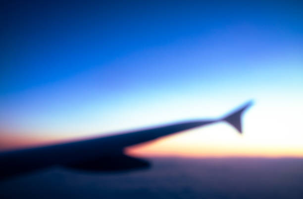 Air travel abstract A defocused view of an airplane wing and a clear sunset horizon beyond. generic description stock pictures, royalty-free photos & images
