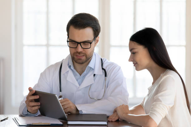 istock Male doctor consult female client using tablet gadget 1311677228