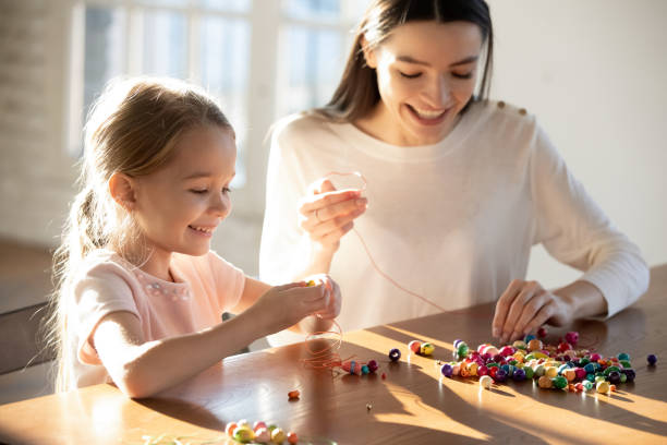istock Happy mom and small daughter make bracelets together 1311677291