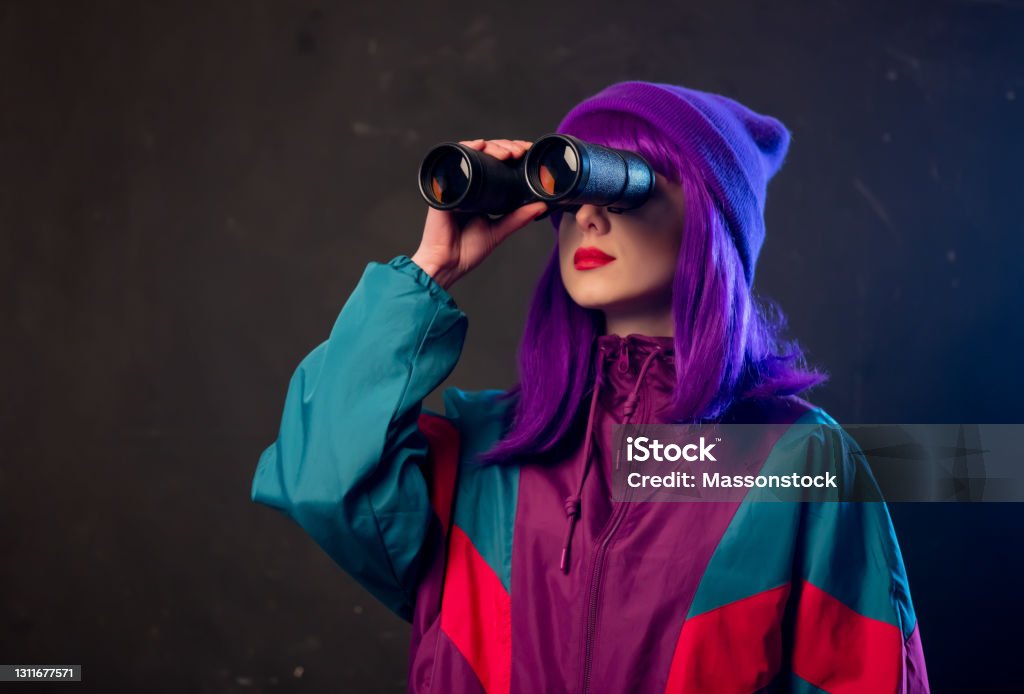 Stilvolle Mädchen in 80er Jahre Trainingsanzug mit Fernglas auf dunklem Hintergrund - Lizenzfrei Fernglas Stock-Foto