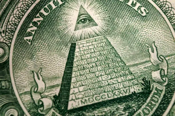 American money, illuminati and mystical symbols concept with macro close up on the all seeing eyeball atop the pyramid on the back of US dollar bill