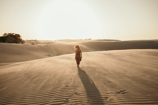 A woman walking on the sand towards the sunset. This place is called Barrinha and is located in Jericoacora.