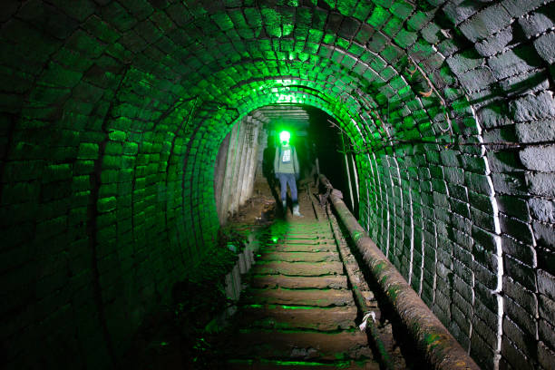 homme dans la combinaison protectrice à l’intérieur de la mine abandonnée d’uranium - flashlight cave spelunking explorer photos et images de collection