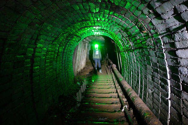 homem em traje de proteção dentro de mina de urânio abandonada - flashlight cave spelunking explorer - fotografias e filmes do acervo