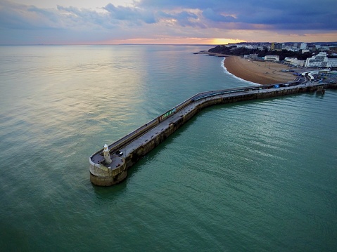 Folkestone Harbour arm jutting out against a colourful sunset in spring.