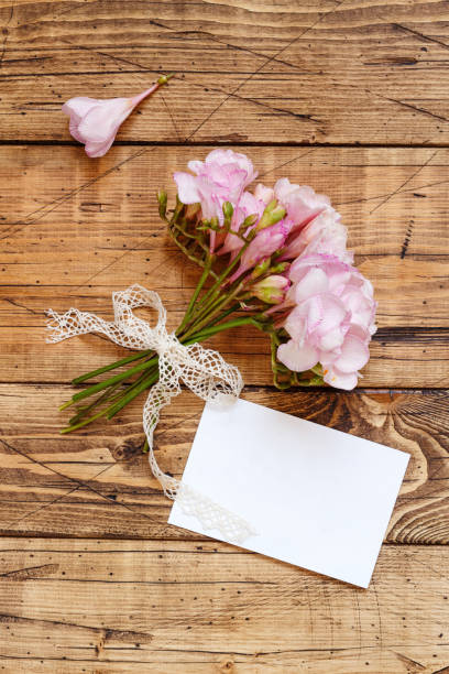 istock Blank card on a wooden table between pink flowers 1311687051