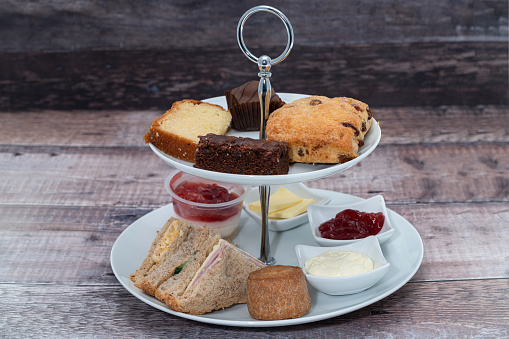 Afternoon tea on a cakestand, sandwiches and scones with clotted cream and jam