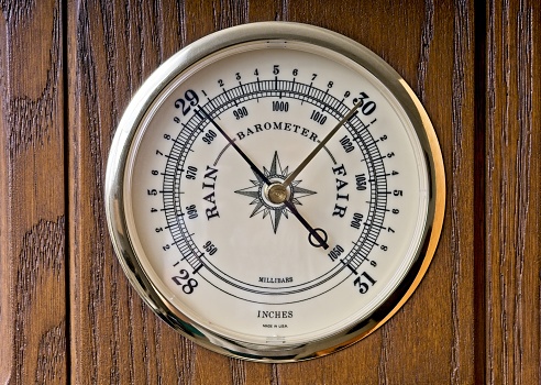 Aneroid barometer gage showing low pressure. Meter showing low millibar or inches of mercury reading signifying an approaching storm or hurricane.