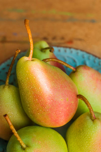 istock Green pears with red sides lying on a turquoise plate in the sunlight. 1311699116