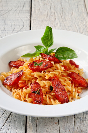 tagliatelle with sauce and slices of pepperoni sausage