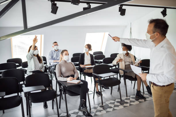 istock People holding distance, wearing protective masks at office. 1311703348