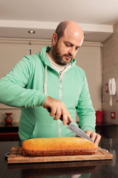 Caucasian man, between 30-39 years old, cutting a sweet cake into portions