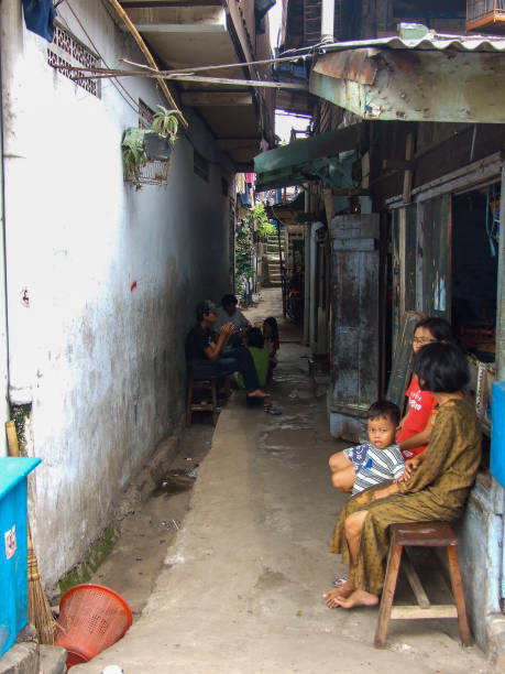 Slum Life - Jakarta Vertical photo of a family sitting outside their small shop in a narrow alley in a poor area in North Jakarta near the Old Port jakarta slums stock pictures, royalty-free photos & images