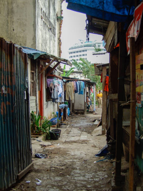 Slum Alley - North Jakarta Vertical photo of a slum alley with people in the far distance in North Jakarta near the Old Port. jakarta slums stock pictures, royalty-free photos & images