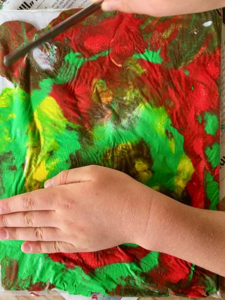 istock Child's Hands Moving Paint Through Plastic Bag on Canvas 1311715639