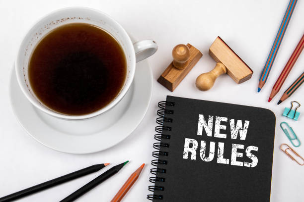 istock New Rules. Black notebook, coffee cup and office supplies on a white table 1311716470