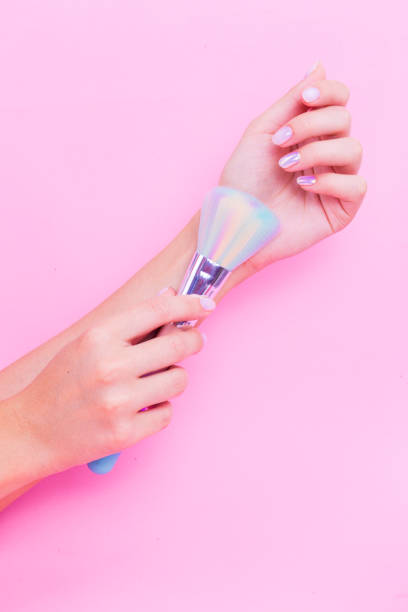 istock Pink brush in hand with pink manicure on a pink background. 1311717465