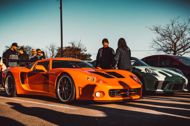 Austin, Texas. usa. January 3rd, 2021. people gathered around cars at a car show in Austin Texas. an orange sports car taken on a cloudless morning.