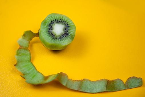 Top view of peeled kiwi on white background. Peel is looking like a snake