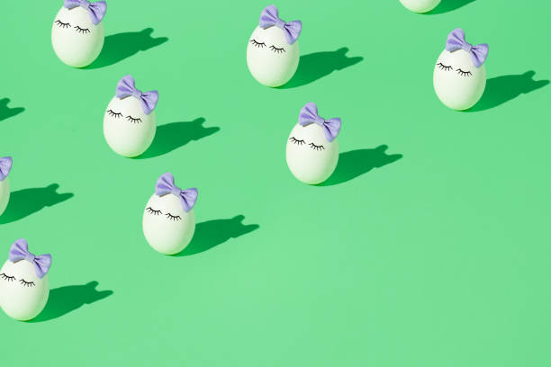 istock Pattern made of White Easter egg with eyelashes and purple bow tie headband on a light green background. Minimal creative holiday or food concept. Copy space. 1311731673