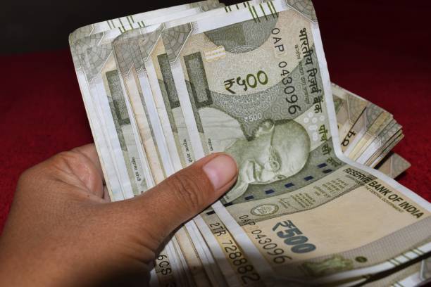 istock 500 indian currency in hand red background 1311732359