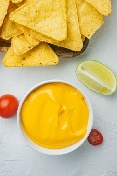 Tortilla chips with cheese dip, on white background, top view or flat lay Tortilla chips with cheese dip sauce, on white background, top view or flat lay cheese dip stock pictures, royalty-free photos & images