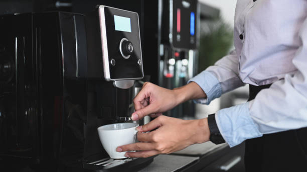 Close up view of businessman making coffee from coffee machine in the office. Close up view of businessman making coffee from coffee machine in the office. coffee maker stock pictures, royalty-free photos & images