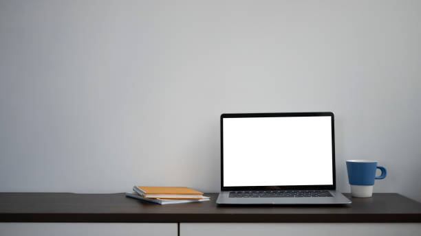 istock Mock up computer laptop with blank screen, coffee cup and notebook on black wooden table. 1311738653