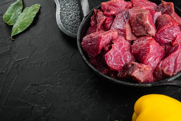 istock Beef chuck stew ingredients , in cast iron frying pan, on black stone background, with copy space for text 1311741020