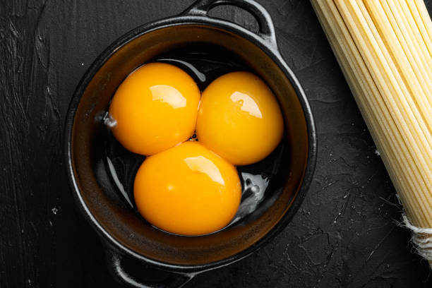 istock Bright yellow egg yolks, on black stone background, top view flat lay 1311742118