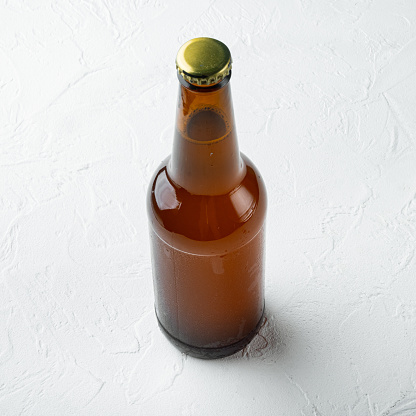 Glass bottles of beer set, on white stone  surface, square format