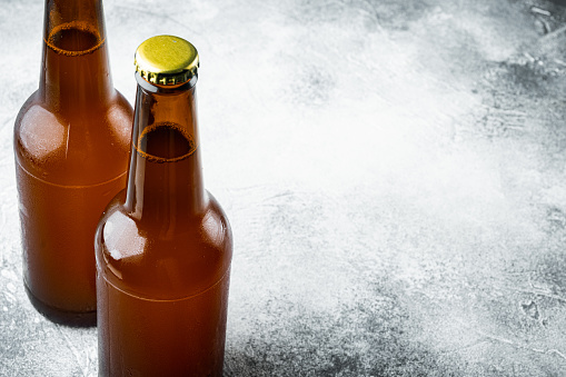 Glass bottles of beer set, on gray stone background, with copy space for text