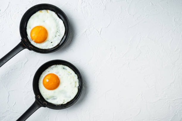 istock Fried eggs with cherry tomatoe and bread for breakfast in cast iron frying pan, on white background, top view flat lay , with space for text  copyspace 1311744062