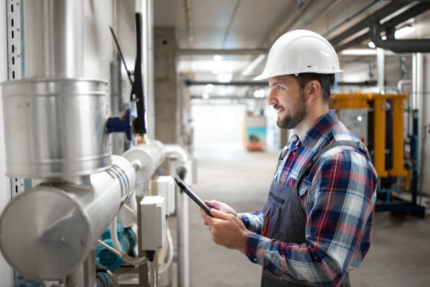istock Portrait of an engineer worker in protective uniform and hardhat checking valves and gas installations in factory boiler room. 1311744877
