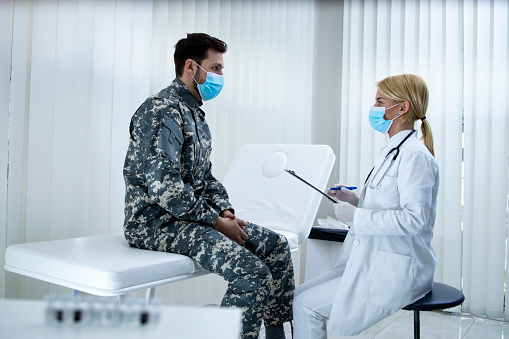Doctor talking with soldier in uniform in the hospital during corona virus.