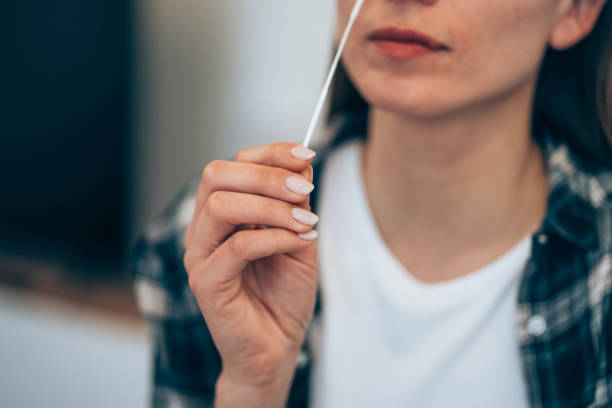 Self-testing for Coronavirus at home. Shot of a woman using cotton swab while doing coronavirus PCR test. Woman takes coronavirus sample from her nose at home. Young woman at home using a nasal swab for COVID-19. self test stock pictures, royalty-free photos & images