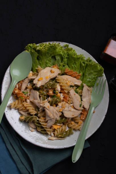 istock Macaroni stir fried with chicken in ceramic plate on black background 1311750360