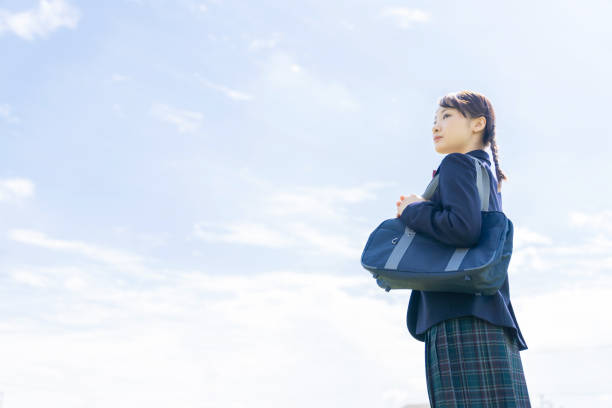 Asian female high school student looking up to sky.