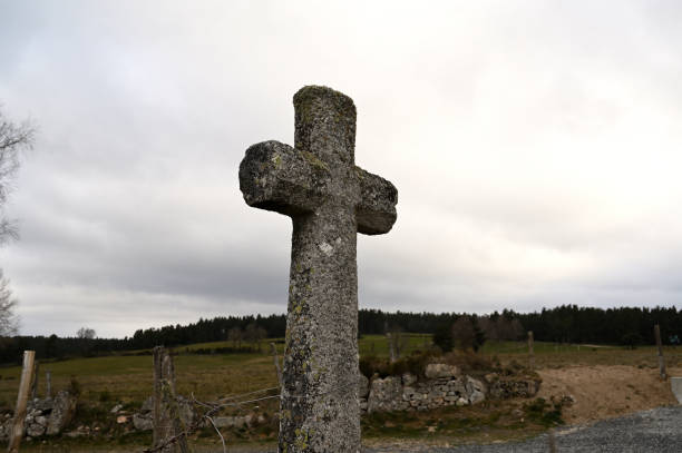 istock Granite stone christian cross in a green field 1311754545