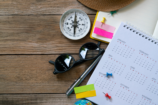 close up of calendar, compass and accessories on the table background, planning for travel concept